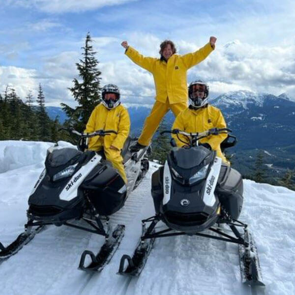 Arms raised on top of a snowmobile at the summit